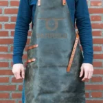 Tablier en cuir BarrelQ cognac porté devant un barbecue extérieur