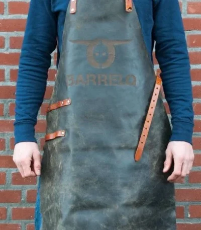 Tablier en cuir BarrelQ cognac porté devant un barbecue extérieur