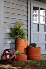 Pflanzkübel en tonneau métal effet rouille dans un jardin moderne